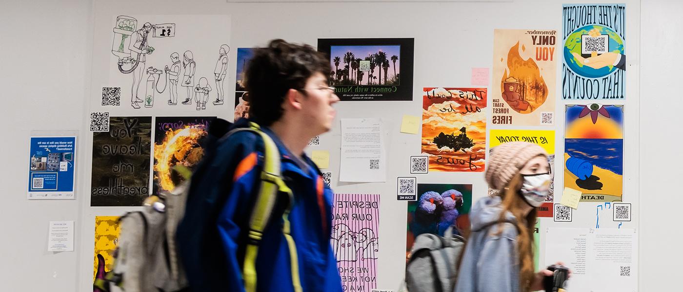 学生们在课间走过走廊，经过张贴在布告栏上的艺术品.